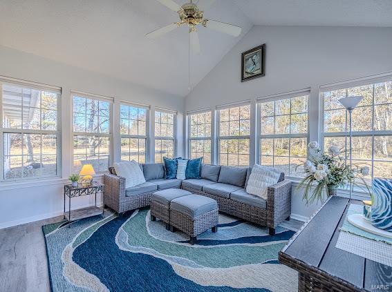 sunroom featuring healthy amount of natural light, high vaulted ceiling, wood finished floors, and baseboards