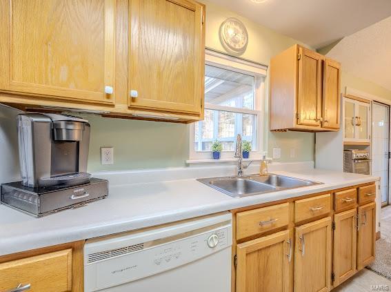 kitchen with white dishwasher, a sink, and light countertops
