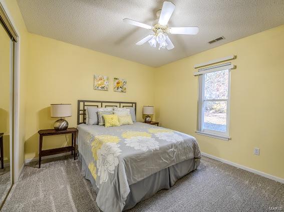 carpeted bedroom featuring a textured ceiling, a closet, baseboards, and ceiling fan