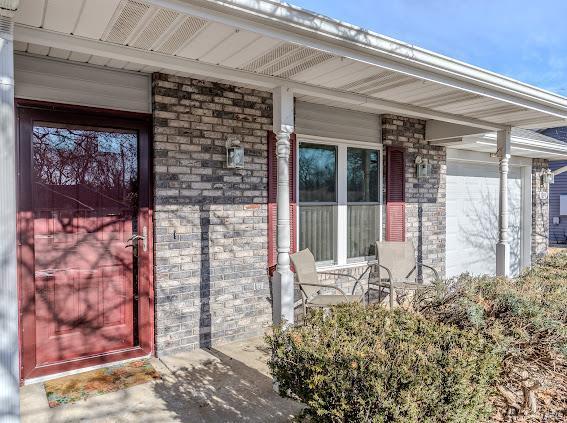 entrance to property with a porch and brick siding