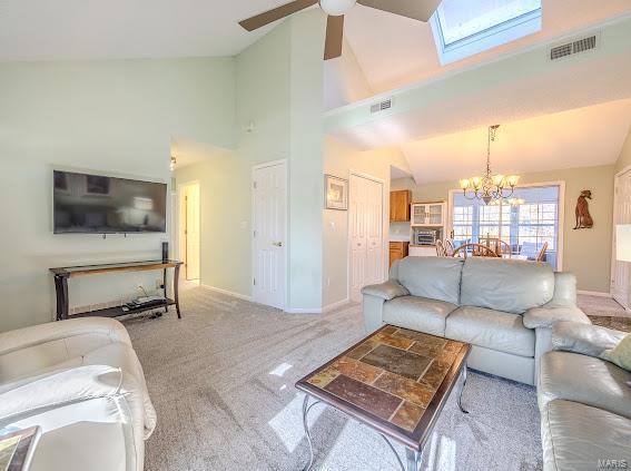 living room featuring high vaulted ceiling, ceiling fan, a chandelier, baseboards, and light colored carpet