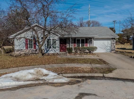 ranch-style home with an attached garage, concrete driveway, and covered porch