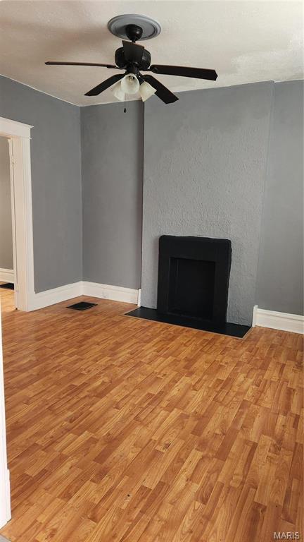 3615 Virginia Ave, Saint Louis, MO 63118 - unfurnished living room with a fireplace with flush hearth, light wood finished floors, ceiling fan, and baseboards
