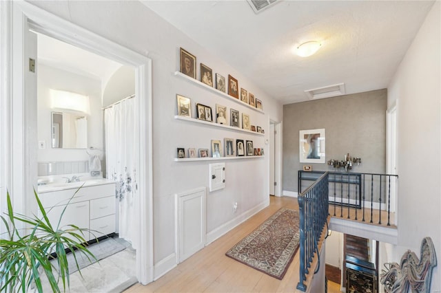 364 Mission Ct, Saint Louis, MO 63130 - hallway featuring attic access, wood finished floors, an upstairs landing, and a sink