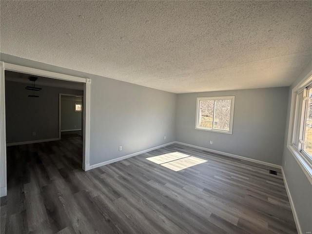 6043 Parkedge Dr, House Springs, MO 63051 - empty room featuring a textured ceiling, dark wood-style floors, healthy amount of natural light, and baseboards