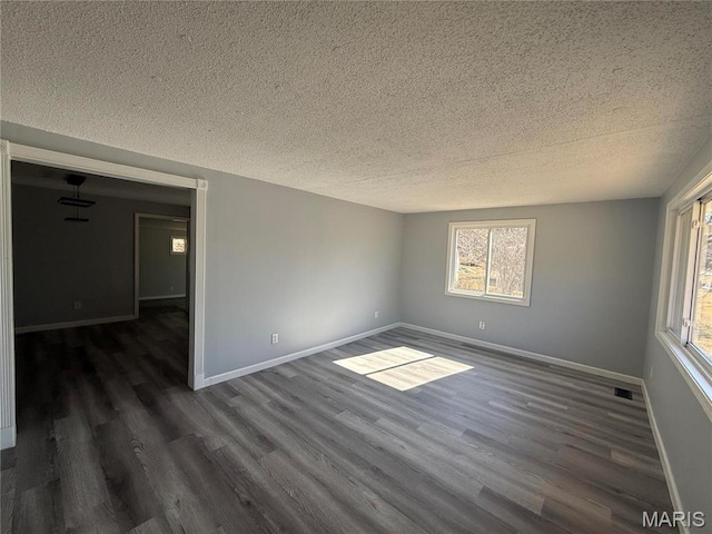6043 Parkedge Dr, House Springs, MO 63051 - empty room with a textured ceiling, dark wood-style flooring, and healthy amount of natural light