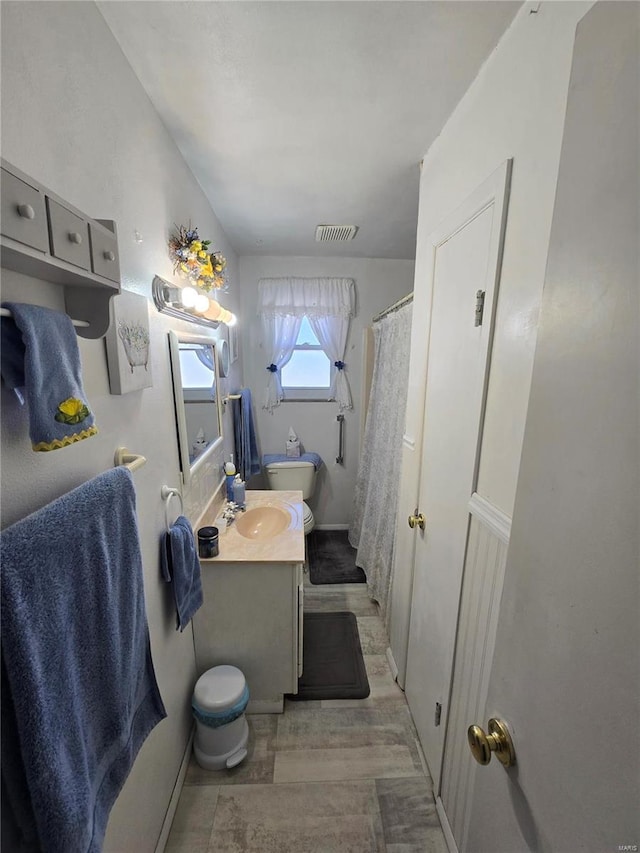 bathroom with toilet, vanity, curtained shower, and wood finished floors