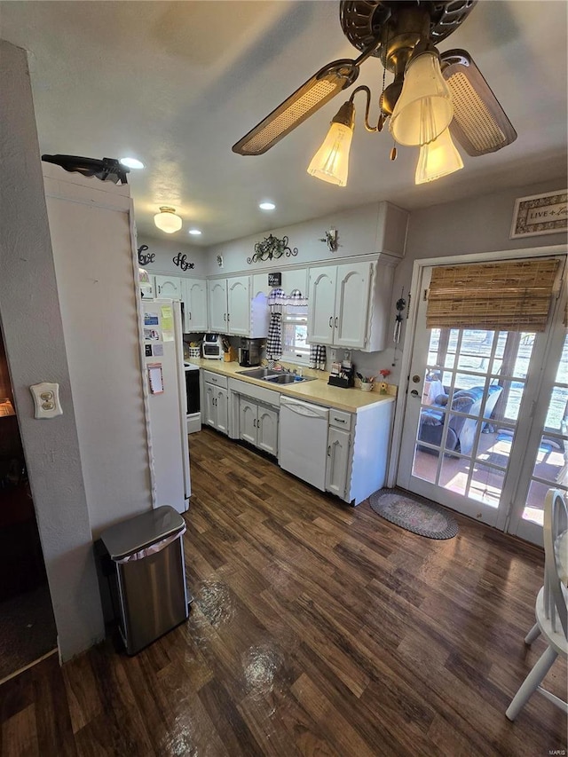 kitchen with white appliances, a sink, light countertops, white cabinets, and dark wood finished floors