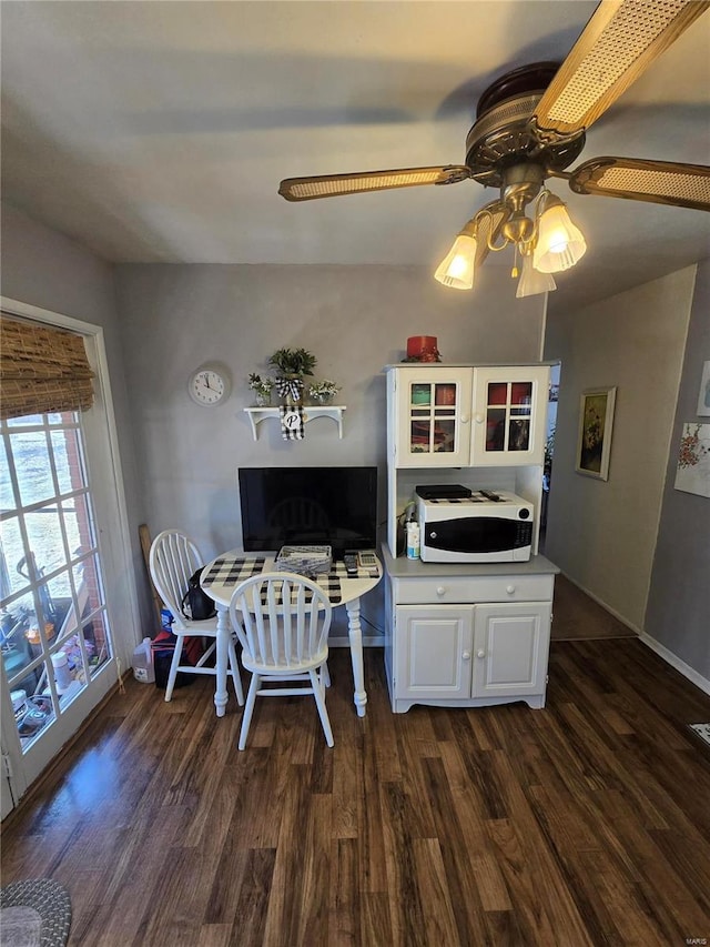 dining space featuring dark wood finished floors, a ceiling fan, and baseboards