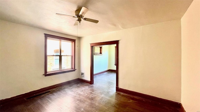 spare room with a ceiling fan, dark wood-style floors, and baseboards
