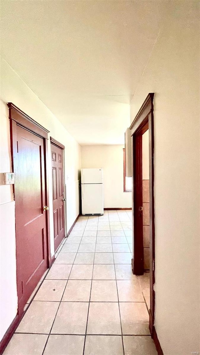 hallway featuring light tile patterned flooring and baseboards