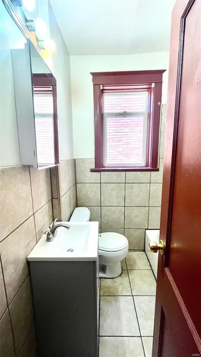 bathroom featuring tile walls, vanity, toilet, tile patterned flooring, and wainscoting