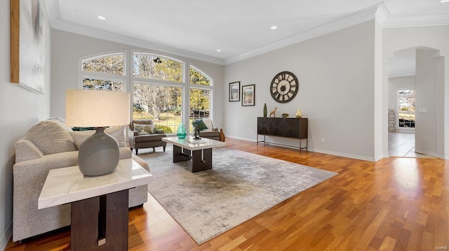 living room with arched walkways, wood finished floors, ornamental molding, baseboards, and recessed lighting