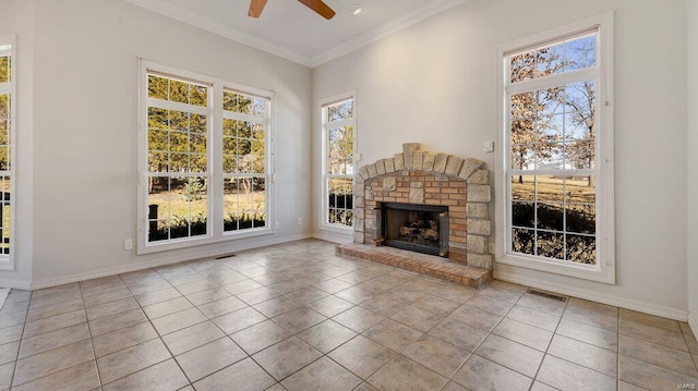 unfurnished living room featuring ceiling fan, plenty of natural light, a fireplace, ornamental molding, and tile patterned flooring