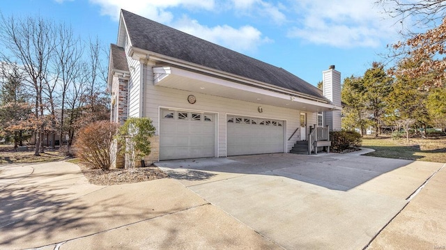 view of side of home with concrete driveway, a shingled roof, and a chimney