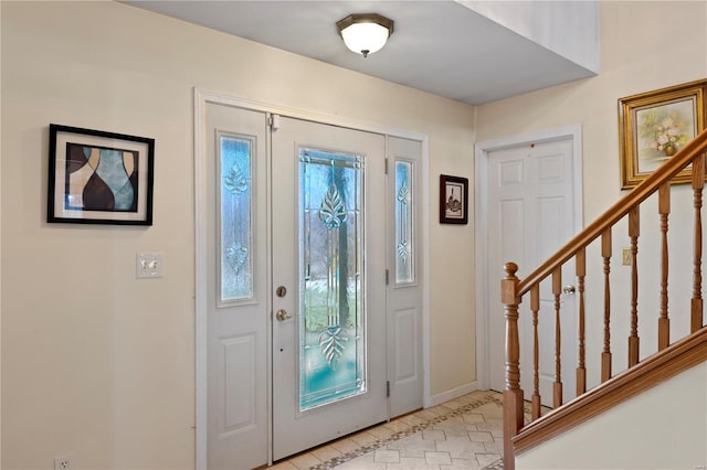 foyer featuring stairs and baseboards