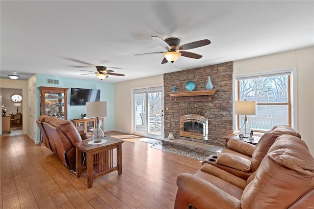 living room with ceiling fan, a fireplace, baseboards, and light wood-type flooring