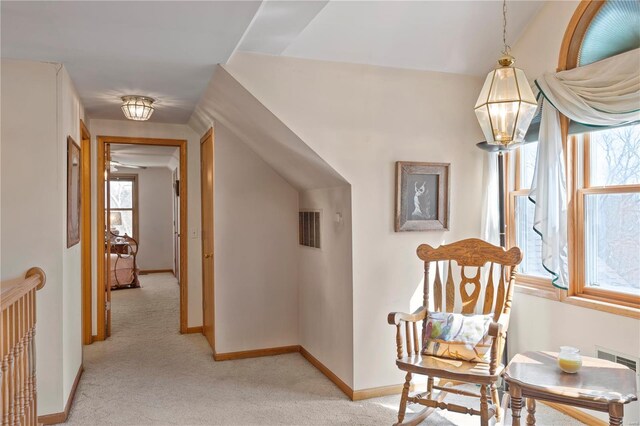 corridor with light colored carpet, baseboards, and vaulted ceiling