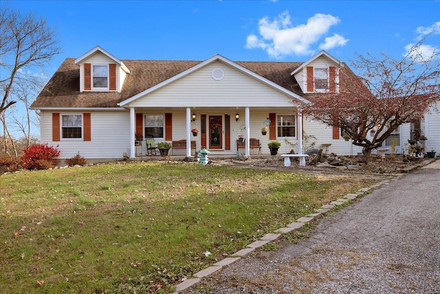 view of front of property with a front lawn, a shingled roof, and covered porch