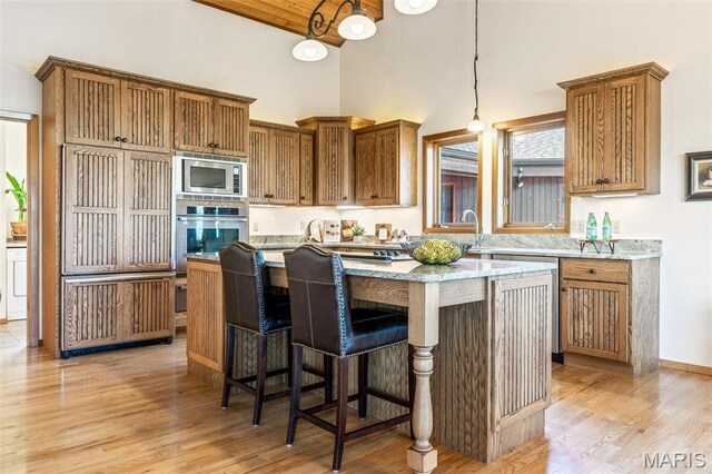 2208 N Konstanz Dr, Innsbrook, MO 63390 - kitchen featuring stainless steel appliances, high vaulted ceiling, a center island, light wood-type flooring, and brown cabinetry
