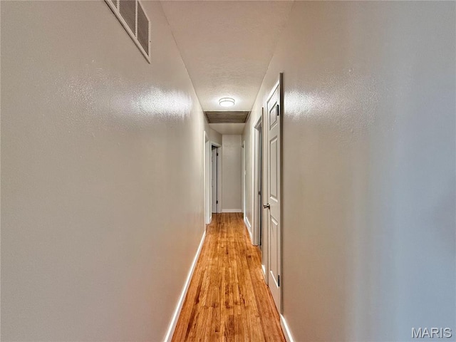 hall with light wood-type flooring and baseboards