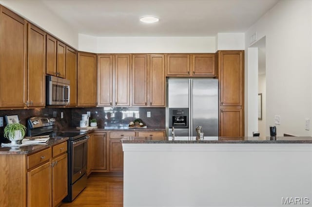 842 N New Ballas Ct Unit 303, Saint Louis, MO 63141 - kitchen with appliances with stainless steel finishes, brown cabinetry, decorative backsplash, wood finished floors, and recessed lighting