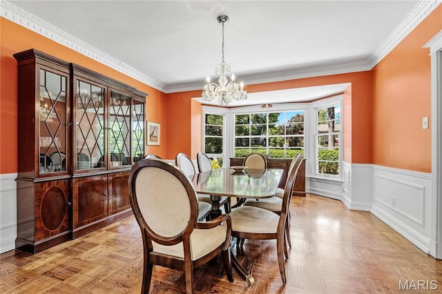 dining space featuring a chandelier, wainscoting, and crown molding