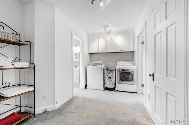 clothes washing area featuring washing machine and dryer, cabinet space, carpet flooring, and baseboards