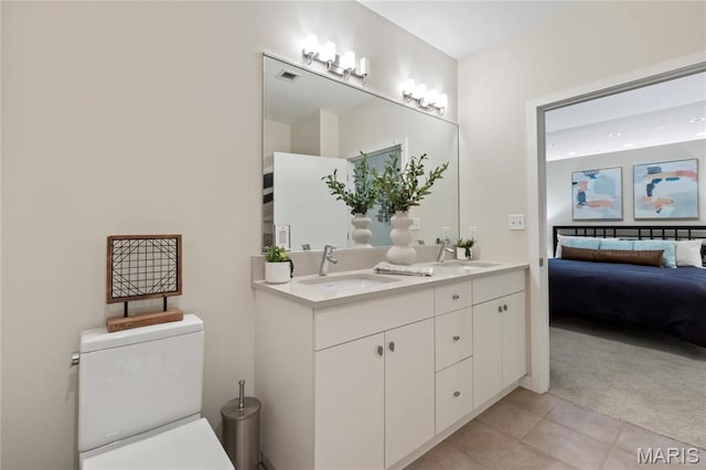 ensuite bathroom featuring tile patterned floors, double vanity, and toilet