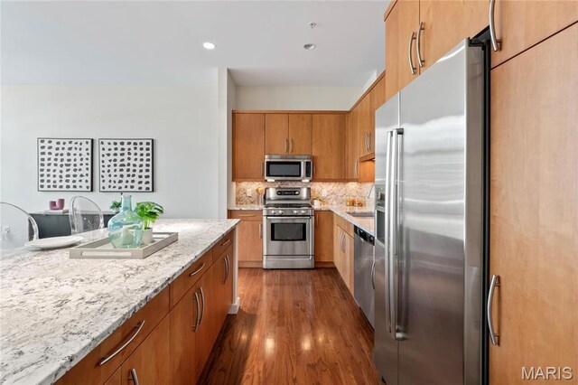 9 N Euclid Ave Unit 508, Saint Louis, MO 63108 - kitchen with appliances with stainless steel finishes, dark wood-style flooring, tasteful backsplash, a sink, and light stone countertops