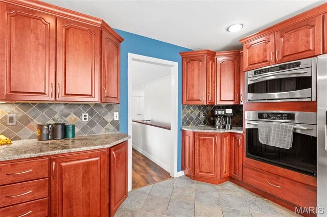 19120 Hawk Mountain Rd, Wildwood, MO 63038 - kitchen featuring light stone counters, stainless steel double oven, backsplash, and baseboards