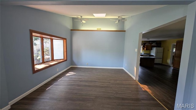 unfurnished room with ceiling fan, dark wood finished floors, and baseboards