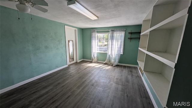 unfurnished room featuring a ceiling fan, wood finished floors, baseboards, and a textured ceiling