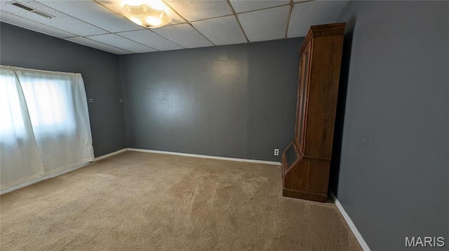 empty room featuring carpet, baseboards, and a drop ceiling