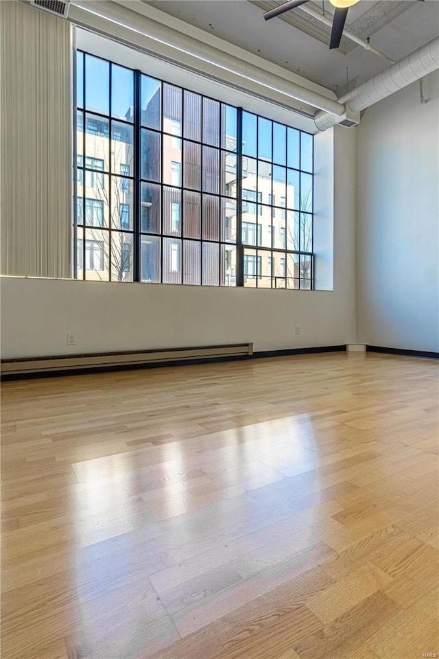 4100 Laclede Ave Unit 110, Saint Louis, MO 63108 - empty room with wood finished floors, a baseboard radiator, and a ceiling fan
