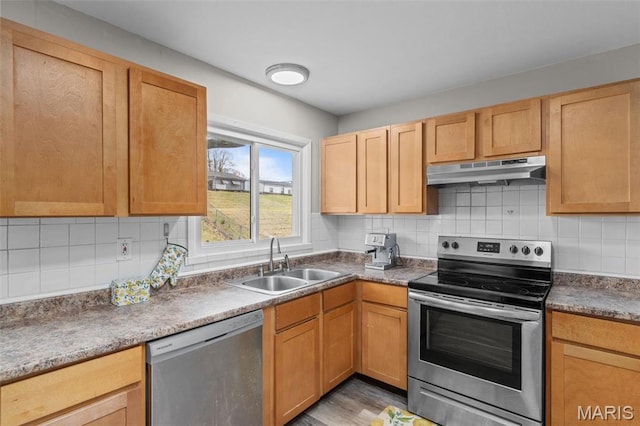 190 Coteau Ln, Florissant, MO 63033 - kitchen with stainless steel appliances, under cabinet range hood, a sink, decorative backsplash, and light wood-type flooring