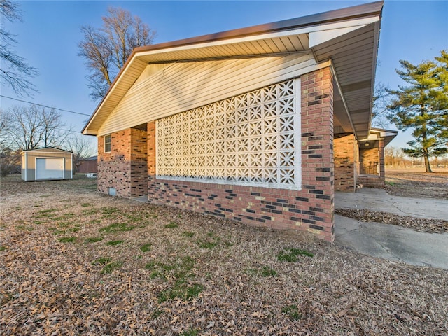 view of side of property featuring an outbuilding, brick siding, and a shed