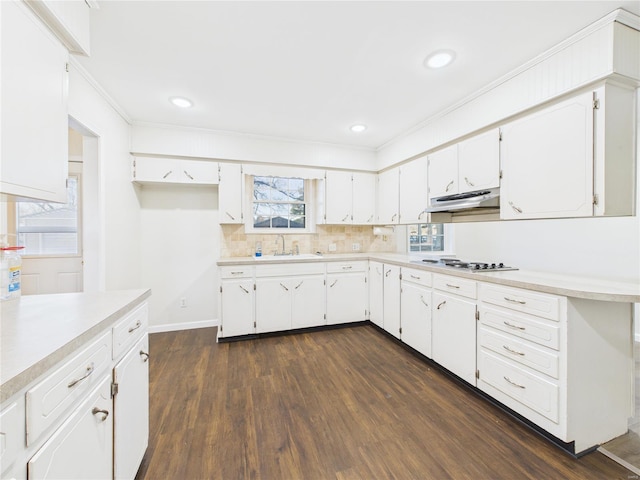 kitchen with under cabinet range hood, stainless steel cooktop, dark wood finished floors, light countertops, and white cabinets