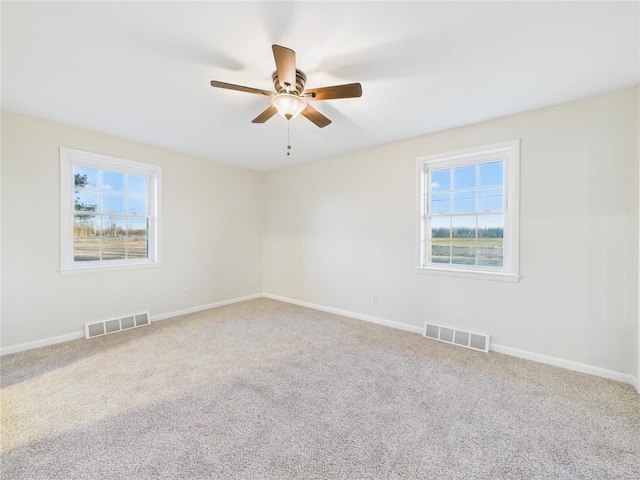 carpeted empty room with healthy amount of natural light, a ceiling fan, and baseboards