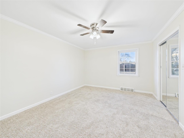 empty room with crown molding, light carpet, baseboards, and a ceiling fan