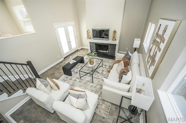 7642 Westmoreland Ave, Saint Louis, MO 63105 - living area with baseboards, a brick fireplace, stairway, a towering ceiling, and french doors