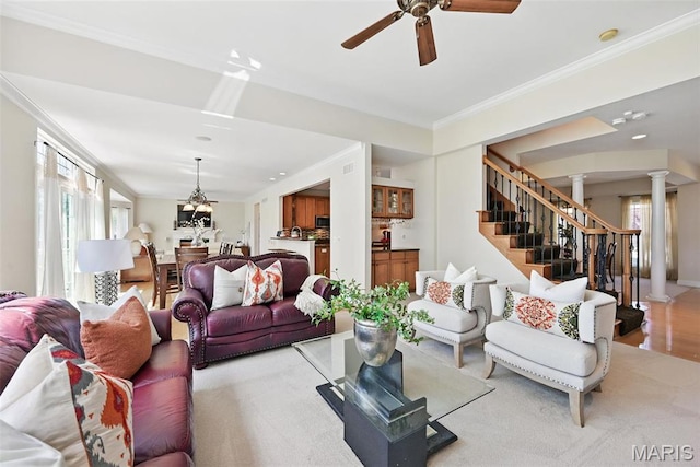 living room with decorative columns, plenty of natural light, stairway, a ceiling fan, and crown molding