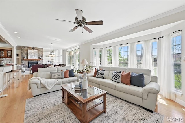 living area featuring crown molding, a fireplace, light wood finished floors, ceiling fan, and recessed lighting