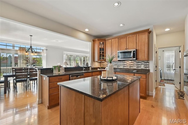 kitchen featuring stainless steel appliances, brown cabinetry, a peninsula, light wood-type flooring, and tasteful backsplash