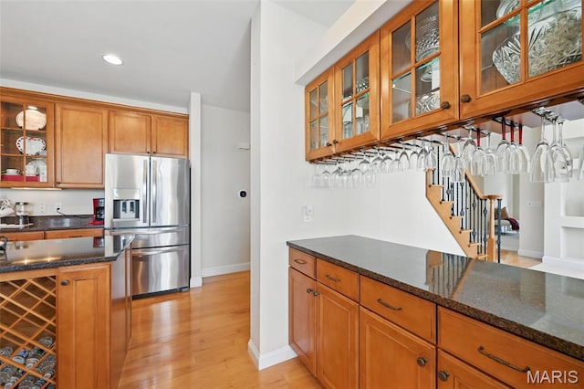 kitchen featuring stainless steel fridge with ice dispenser, brown cabinets, baseboards, dark stone countertops, and recessed lighting