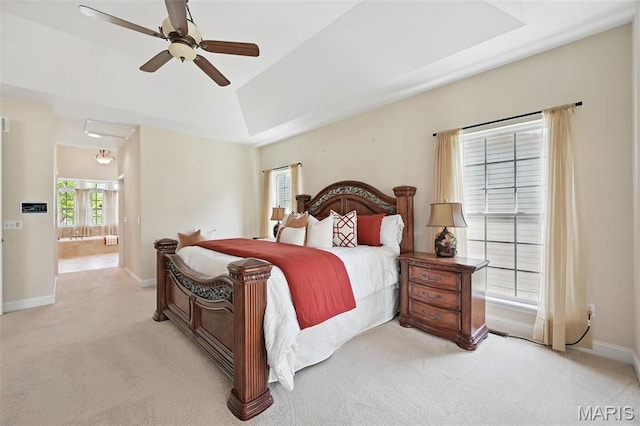 bedroom featuring light carpet, baseboards, vaulted ceiling, ensuite bath, and ceiling fan