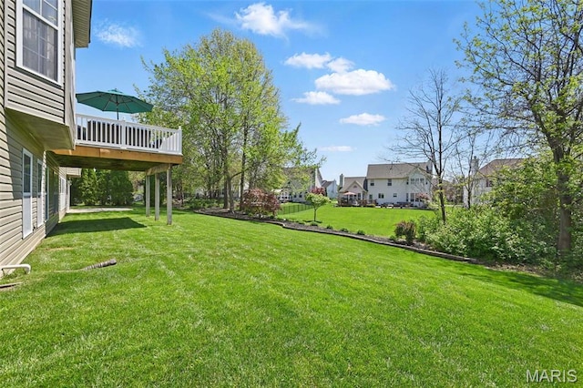 view of grassy yard with a wooden deck and a residential view