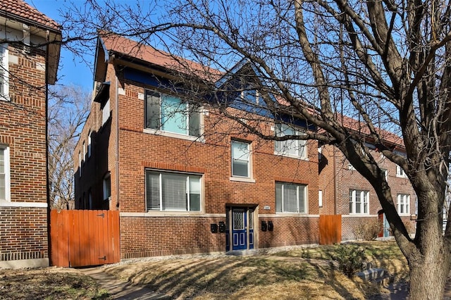 view of property exterior with brick siding, fence, and a gate