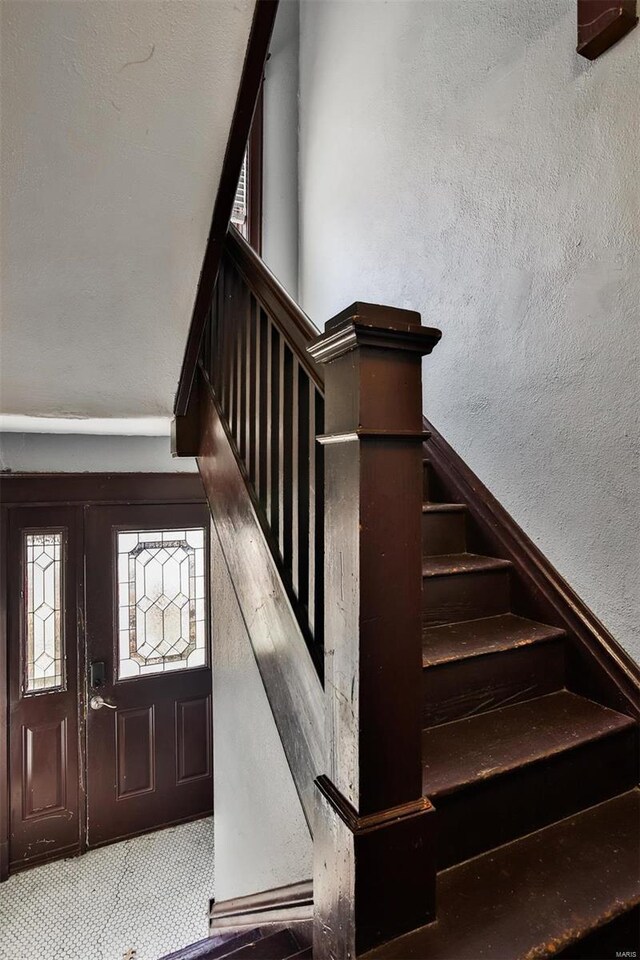 stairway featuring a textured wall and carpet