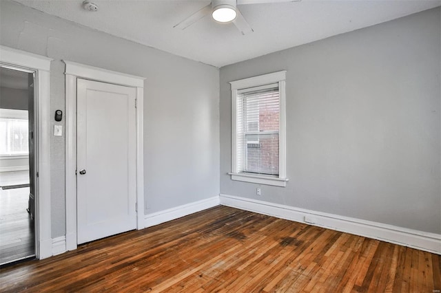 empty room featuring a ceiling fan, dark wood-style floors, baseboards, and a smoke detector